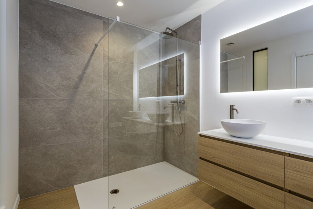 Moderne badkamer met inloopdouche en verlichte spiegel, strak design en natuurlijke materialen.